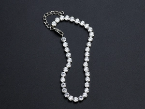 Macro view of silver tennis bracelet with sparkling stones on dark textured background