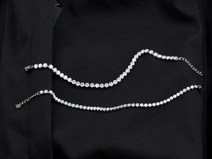 Detail of two silver tennis bracelets with sparkling cubic zirconia on black fabric