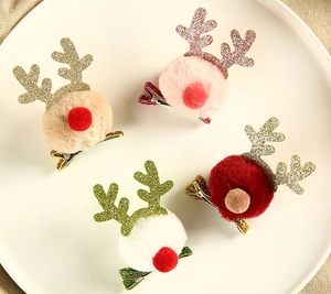 Close-up of colorful plush Christmas reindeer antler hair clips on a white plate