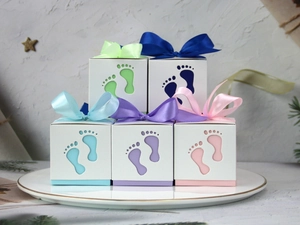 Detailed laser-cut baby footprint gift boxes in pastel colors with matching satin ribbons