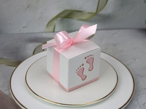 Detailed view of pink hollow baby footprint candy box on a gold-rimmed ceramic plate