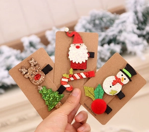 Close-up of festive Christmas hair clips featuring felt reindeer and Santa on card