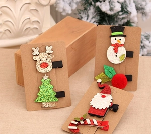 Detail of Christmas hair clips featuring colorful reindeer and Santa Claus on cards