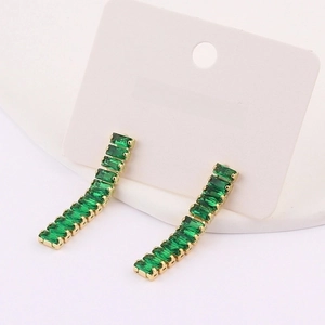 Detail of long curved gold earrings featuring emerald-cut green crystal stones