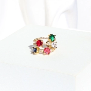 Detail of gold-plated multi-layer ring with five colorful oval stones on white stone base