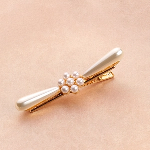 Detail of elegant gold alloy hair clip with white pearls on pink silk background