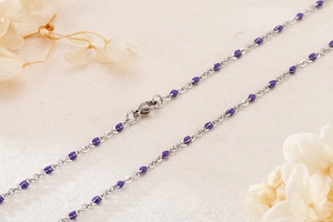 Macro detail of silver titanium steel chain with purple resin beads and lobster clasp