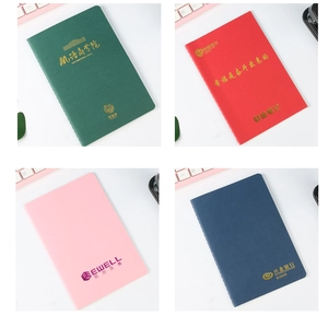 Detail of four colorful notebooks with custom gold-stamped logos on desk surface