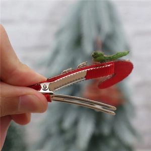 Detail of a Christmas themed hair clip with red and green fabric held in hand