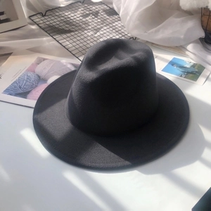 Detailed view of black wool fedora hat on white desk with aesthetic props