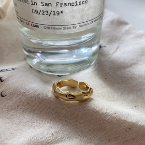 Detailed view of the golden textured bamboo style adjustable ring on soft fabric
