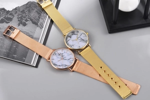 Flat lay of gold and rose gold quartz watches with marble dials and mesh bands