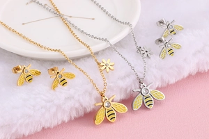 Detailed view of bee jewelry set with gold and silver necklaces and matching stud earrings
