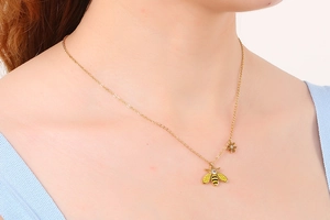 Detail of gold bee necklace with crystal wings on model's neck for elegant styling