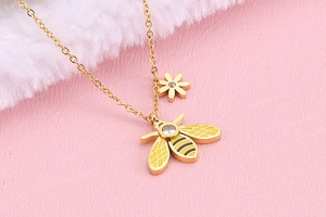 Detailed close-up of a gold-plated bee and flower pendant necklace with yellow enamel