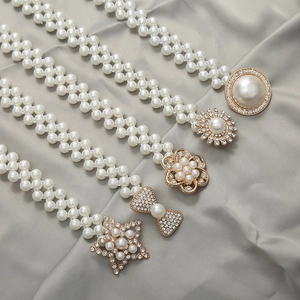 Detailed view of elastic pearl belts with sparkling rhinestone-inlaid gold buckles