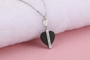Gros plan du collier en argent avec pendentif cœur gravé I LOVE YOU sur peluche blanche