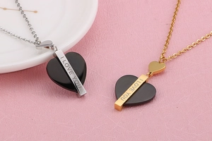 Détail de colliers cœur en argent et or avec gravure I Love You sur fond rose doux