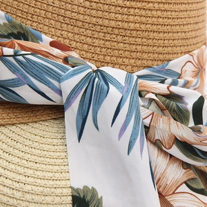 Macro shot of tight natural straw weave and tropical floral print ribbon on summer hat