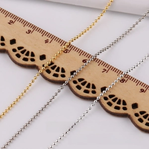 Detailed close-up of 3.2mm gold and silver bead chains on a vintage wooden ruler
