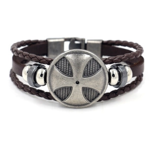 Dettaglio del bracciale multistrato in pelle marrone con scudo a croce in metallo retrò