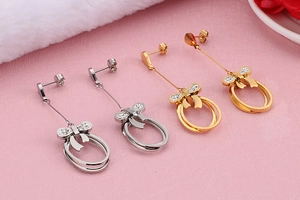 Detailed view of gold and silver bow earrings with double ring pendants and zircons