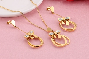 Macro detail of golden bow necklace and earrings set with white zircon inlay