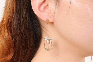 Close-up of golden bow earrings with sparkling rhinestones and dangling circular rings