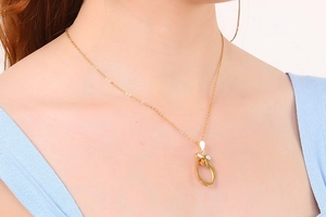 Detail of a gold bow pendant necklace with white crystals on a model neckline