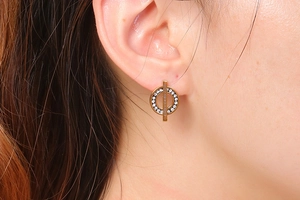 Close-up of golden hollow circle earrings with silver rhinestones on model's ear
