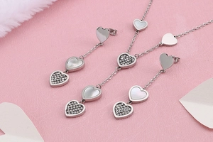 Detailed view of silver heart-shaped necklace and earrings set with shell inlay and crystals