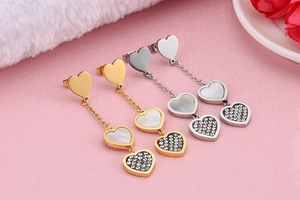 Detail of gold and silver heart earrings featuring shell inlay and sparkling rhinestones