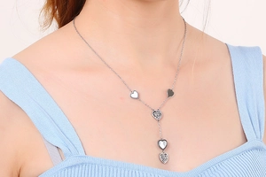 Close-up of silver heart pendant necklace on model wearing blue ribbed top