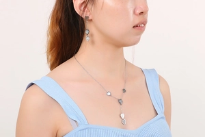 Close-up of heart-shaped necklace and shell earrings set worn by a model