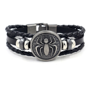 Dettaglio del bracciale in pelle nera multistrato con emblema a ragno argento e treccia