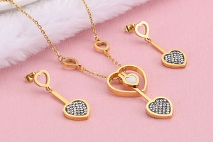 Détail de parure de bijoux cœur doré avec nacre blanche et strass étincelants
