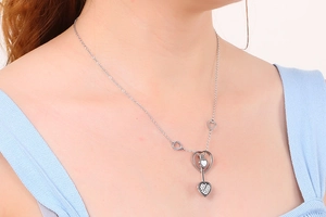Détail d'un collier pendentif cœur argenté avec strass porté par un mannequin
