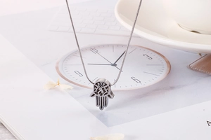Detailed close-up of a silver Hamsa Hand pendant on a delicate snake chain necklace