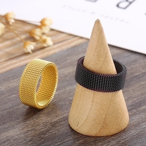 Gold and black mesh stainless steel rings displayed on wooden cones with flowers