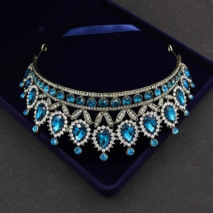 Detailed macro of Baroque gold crown with teardrop blue crystals on blue velvet