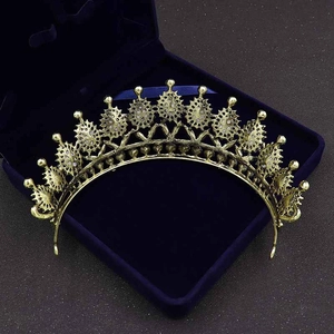 Detailed top view of a gold baroque crown with teardrop crystals in a blue velvet box