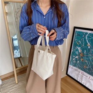 Detail of a minimalist white canvas lunch bag featuring a magnetic closure and sturdy handle
