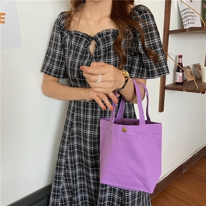 Detail of purple canvas lunch bag with metal button closure and durable handle