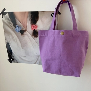 Detailed close-up of a purple canvas bento bag featuring a bronze metal snap button