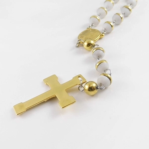 Detail of polished gold cross pendant with white rosary beads and metal caps