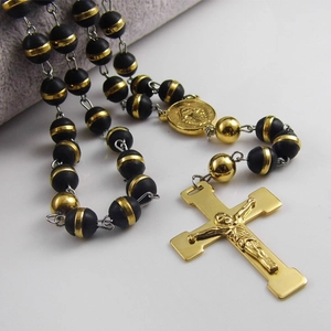 Close-up of golden crucifix and Virgin Mary medal on black beaded rosary necklace