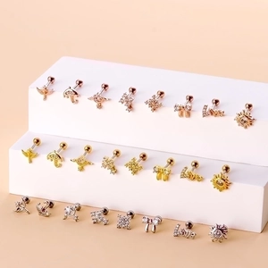 Surgical steel stud earrings set featuring zircon bow and sun designs on display stand