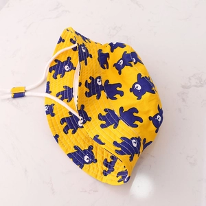 Detail of yellow kids bucket hat with blue bear print and white adjustable chin strap