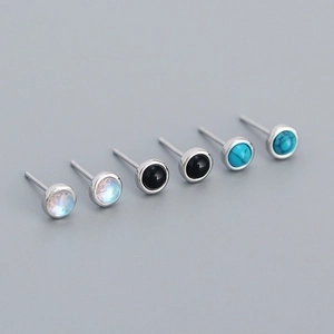 Macro shot of silver stud earrings featuring opal, onyx, and turquoise stones