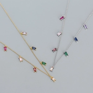 Flat lay of gold and silver S925 necklaces with vibrant colorful zircon stone pendants